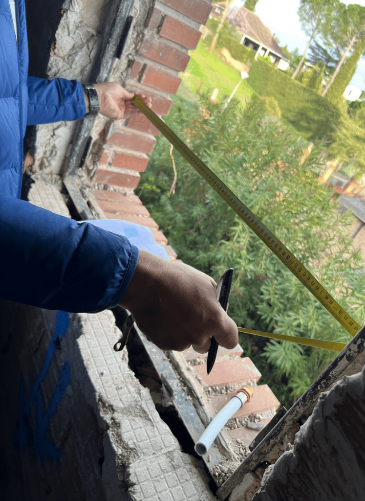 Medición de hueco de ventana en obra de reforma con cinta métrica.