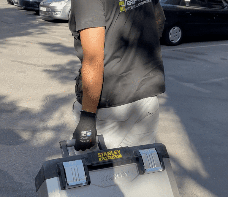 técnico con camiseta de TermProtect arrastrando caja de herramientas Stanley FatMax en parking