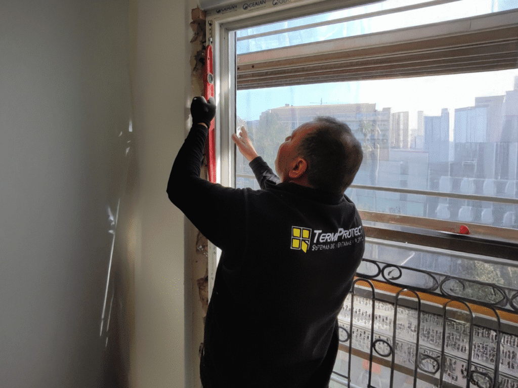 Instalador profesional de Termprotect verificando la nivelación de una ventana de PVC o aluminio durante el proceso de instalación para mejorar el aislamiento térmico y acústico.